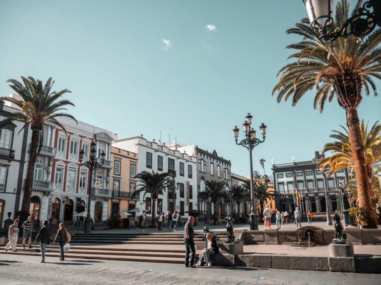 A vibrant day in a city square with people and palm trees in Canary Islands, Spain.